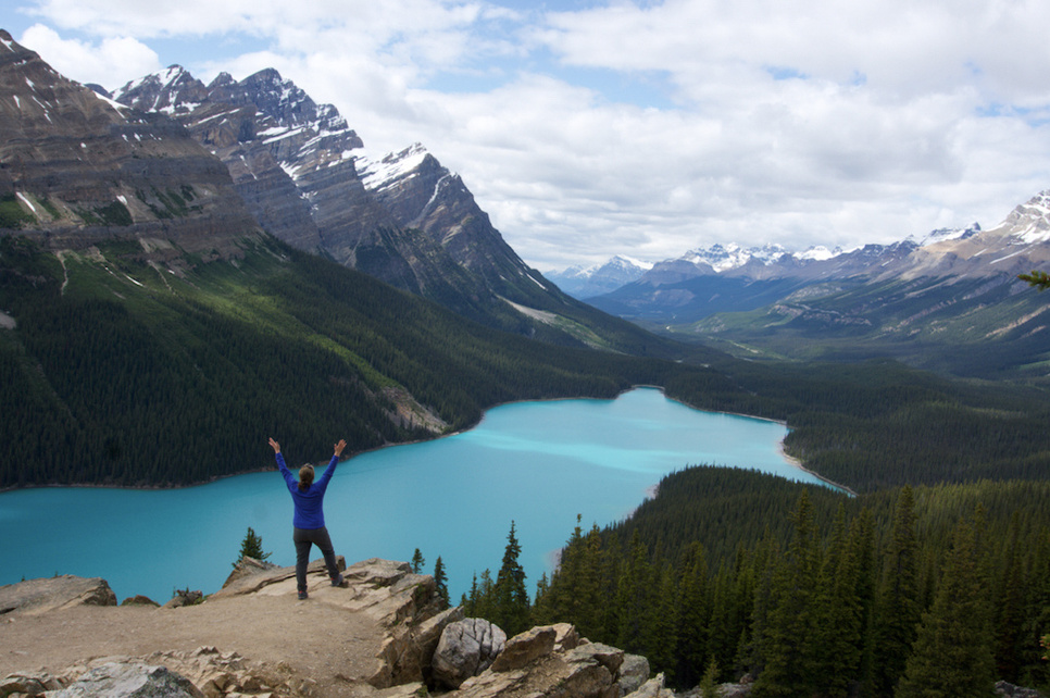 a person standing on top of a mountain overlooking a turquoise lake